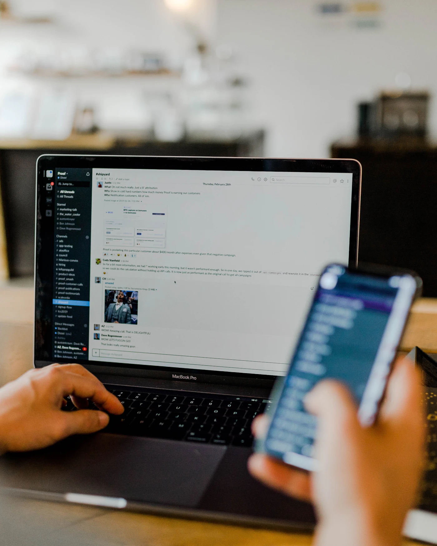 Persona revisando redes sociales en el móvil frente a un portátil